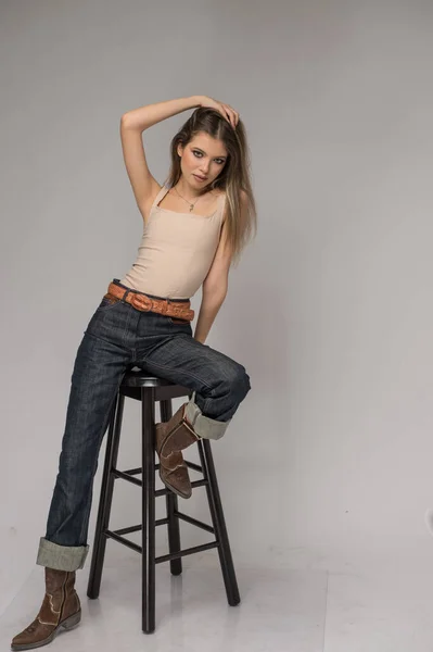 Atrakcyjna Dziewczyna Niebieskich Dżinsach Długich Nogach Stwarzająca Wyzwania Przed Tłem — Zdjęcie stockowe
