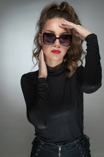 Vrouw Met Zonnebril Zwarte Blouse Tegen Een Grijze Achtergrond Stijl — Stockfoto