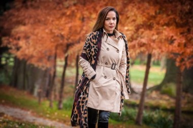 Ormanda ceketli genç bir kız. Parkta mantolu moda kadını. Açık havada beyaz önlüklü genç bir manken. Güz parkında şemsiyeli leopar desenli ceketli güzel bir kadın.