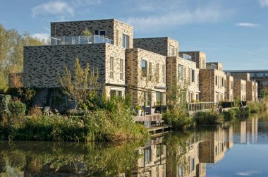 Utrecht, Hollanda, 13 Kasım 2022: Leidsche Rijn Mahallesi 'ndeki bitişik gölete yansıyan ahşap teraslı tuğla kübist evler