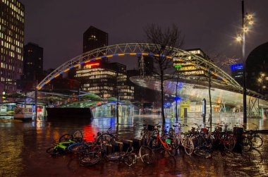 Rotterdam, Hollanda, 16 Ocak 2023: Bisikletler, bazıları park etmiş, bazıları düşmüş, yağmurlu bir kış sabahı Blaak tren istasyonunun yanındaki meydana.