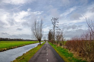 Two lane asphalt road for bicyclists and hikers in a flat polder landscape in Krimpenerwaard region near Gouda, The Netherlands