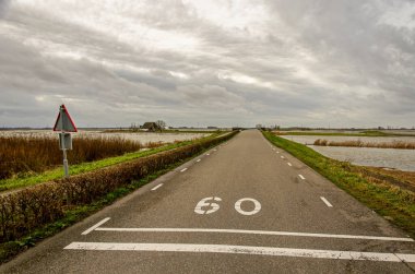 Werkendam, Hollanda, 29 Aralık 2024: Biesbosch Ulusal Parkı 'ndaki Noordwaard bölgesinde nehir projesi için yer alan odanın bir parçası olarak nehir ile sel baskınları arasındaki asfalt yol 