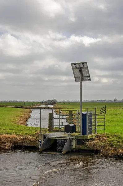 Small pumping station draining water from a set of ditches into a larger canal in a polder landscape near Schoonhoven, The Netherlands