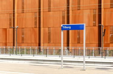 Tilburg, Hollanda, 10 Eylül 2024: istasyon adı Tilburg olan bir platform tabelası, arka planda korse çelikten bir garaj cephesi var.