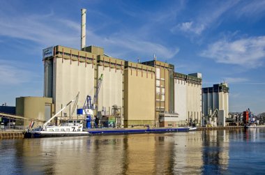 Lochem, Hollanda, 2 Şubat 2025: Güneşli bir kış gününde büyük siloları ve diğer endüstriyel mirasıyla şehrin kuzeyindeki kanal boyunca görüş