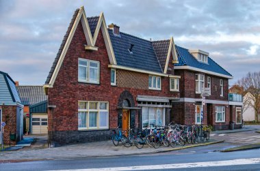 Delfgauw, Hollanda, 12 Ocak 2025: tuhaf şekilli ve önünde bisikletler park edilmiş ev grubu, yolun bir virajında.