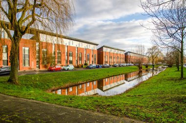 Pijnacker, Hollanda, 12 Ocak 2025: Bir banliyö mahallesindeki kanal boyunca milenyum döneminden itibaren sıra konutlar