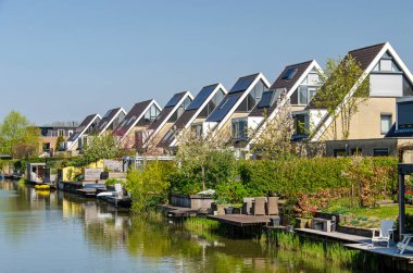 Vleuten, Hollanda, 12 Nisan 2025: eğimli çatıları ve bahçeleri olan evler ve kanaldaki döküntüler