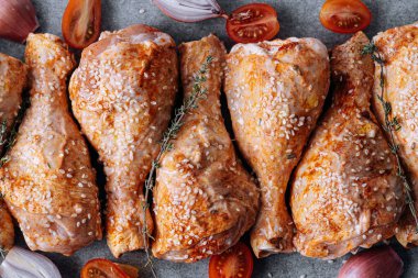 chicken drumsticks with spices, paprika and sesame seeds, ready to bake on a baking sheet