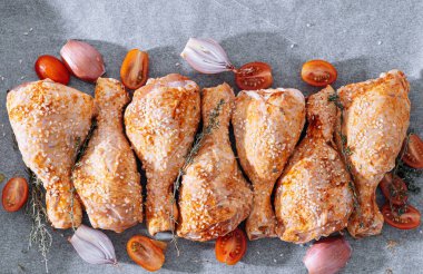 chicken drumsticks with spices, paprika and sesame seeds, ready to bake on a baking sheet