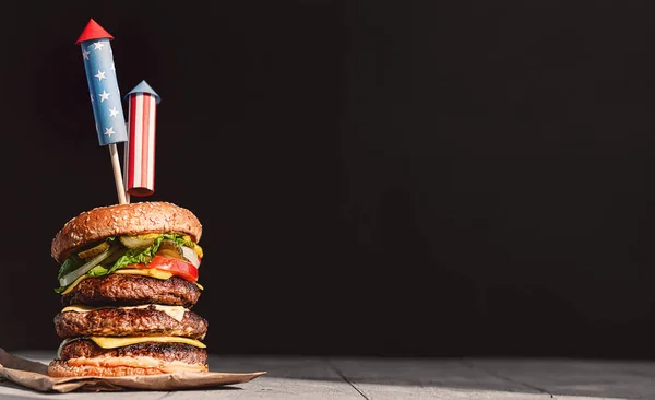 Ein Großer Burger Mit Drei Saftigen Rindfleischpasteten Die Mit Feuerwerksspießen lizenzfreie Stockbilder