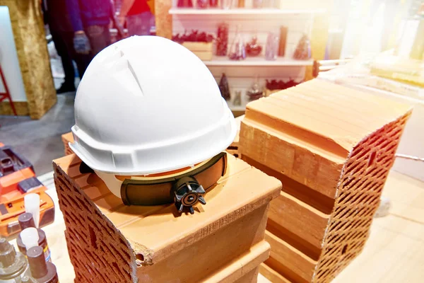 Builder safety helmet, tools and bricks in construction store