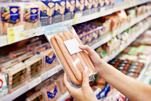 Sausages in the hands of a buyer in a supermarket