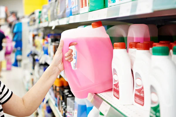 Woman hand with windshield washer fluid in the supermarket