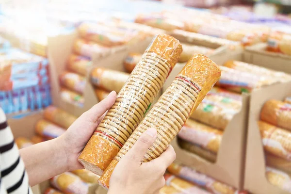 Packed biscuits in hands of buyer in shop