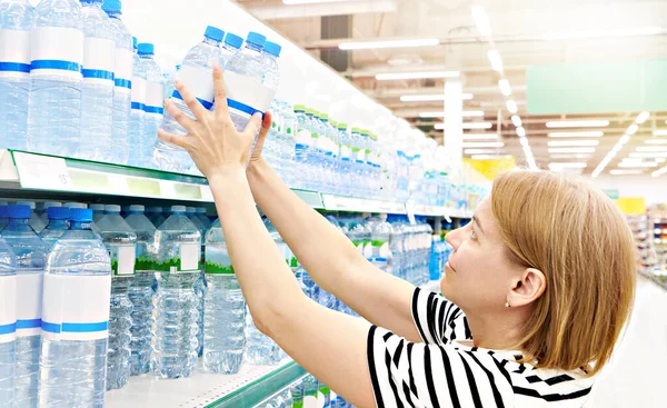 Woman shopper with bottles of water in shop