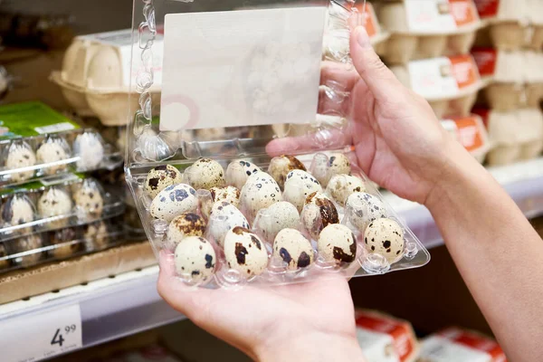 Hands woman with packages of quail eggs in the store