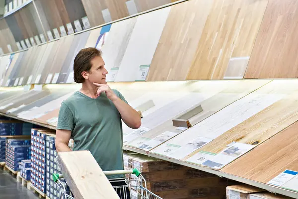 Man chooses floor laminate for home in store