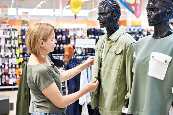 Woman chooses a men\'s shirt in a store
