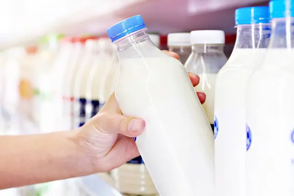 Woman chooses milk and dairy products at the grocery store