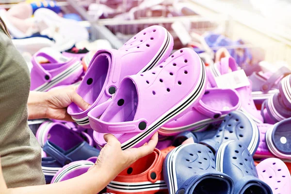 女人在服装店里选择塑料拖鞋 免版税图库图片