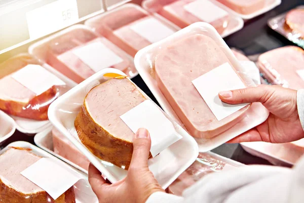Hands with pork ham at store