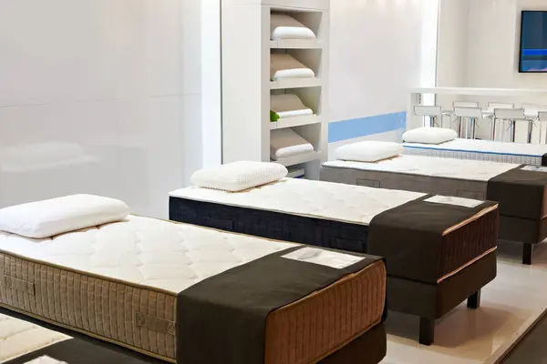 Modern beds with mattresses and pillows in the store