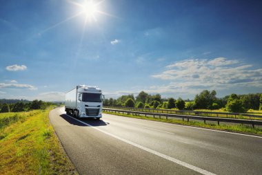 Gün batımında kırsal alanda bir otoyol üzerinde büyük bir nakliye kamyonu.