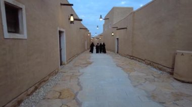 A group of Saudi women in abayas walking in the street of At-Turaif UNESCO World Heritage Site