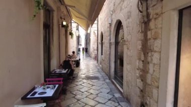 Dubrovnik, Hırvatistan - 7 Ağustos 2023: Eski Kentte kafeler ve dükkanlar bulunan dar sokakta bir kamera hareket ediyor