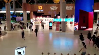 İstanbul, Türkiye - 7 Ağustos 2024: İstanbul Uluslararası Havalimanı 'nda kafeleri ve vergisiz dükkanları olan büyük bir plaza, yükselen yürüyen merdivenden manzaralı