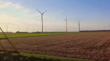 Tarlalar ve Kuzey Hollanda 'da bir rüzgar parkı gün batımında bir hız treninin vitrininde görüldü. 