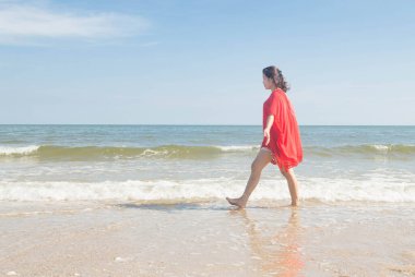 Kumsalda yürüyen bir kadın.