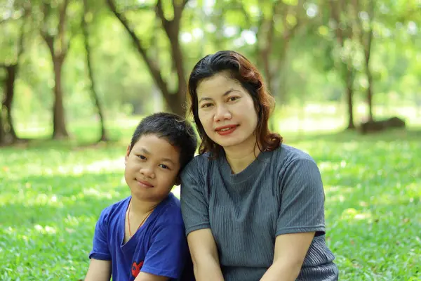 庭の草の上に座っている母と息子 ストック写真
