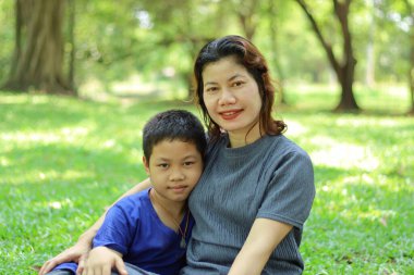 Anne ve oğlu bahçede çimlerin üzerinde oturuyor.