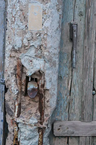 Paslı kilidi ve asma kilidi olan eski ahşap kapı, yakın plan.