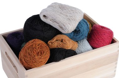 Beyaz arka planda ahşap bir kutuda yün iplik..