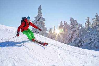 Yokuş aşağı mavi gökyüzü karşı yüksek dağlarda kayak kayakçı.