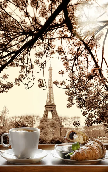 クロワッサンとホットコーヒーは フランスのパリにあるエッフェル塔に対する木製のトレイで提供されています — ストック写真