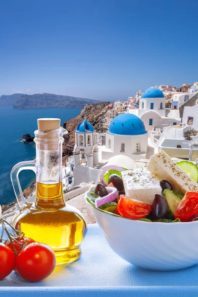 Greek food against famous churches in Oia village on Santorini island in Greece