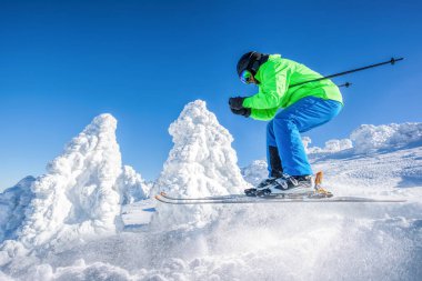 Skier skiing downhill in high mountains against against the fairytale winter forest.