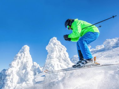 Skier skiing downhill in high mountains against against the fairytale winter forest.