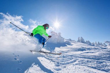 Skier skiing downhill in high mountains against against the fairytale winter forest.