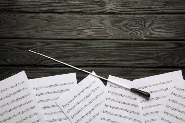 Orkestra şefinin copu ve notaları siyah ahşap masada, düz yerde. Metin için boşluk
