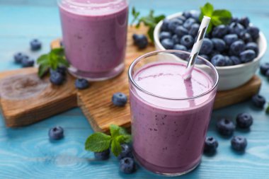 Bir bardak nane ve turkuaz ahşap masada taze böğürtlenli yabanmersinli smoothie.