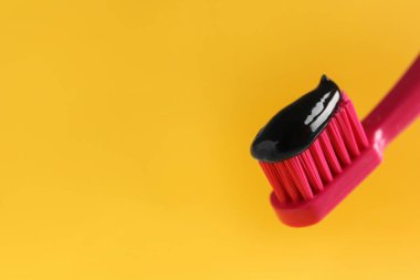 Sarı arka planda kömür diş macunu ile fırçala, yakın plan. Metin için boşluk