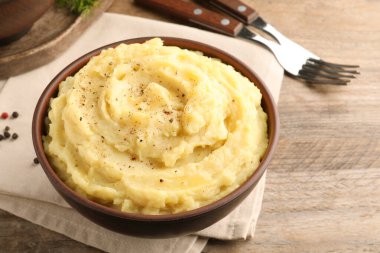 Tahta masada servis edilen bir kase lezzetli patates püresi ve karabiber.