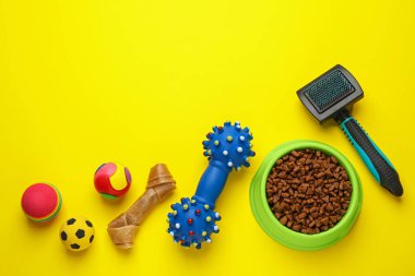 Düz kompozisyon, evcil hayvan oyuncakları ve beslenme çanağı sarı arka planda, metin için boşluk