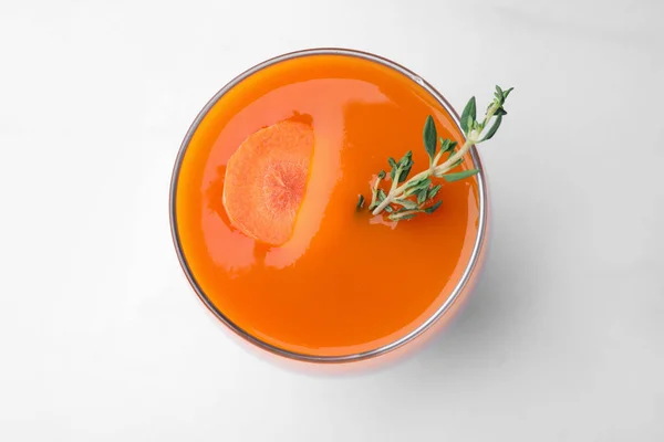 stock image Glass with healthy carrot juice on white table, top view